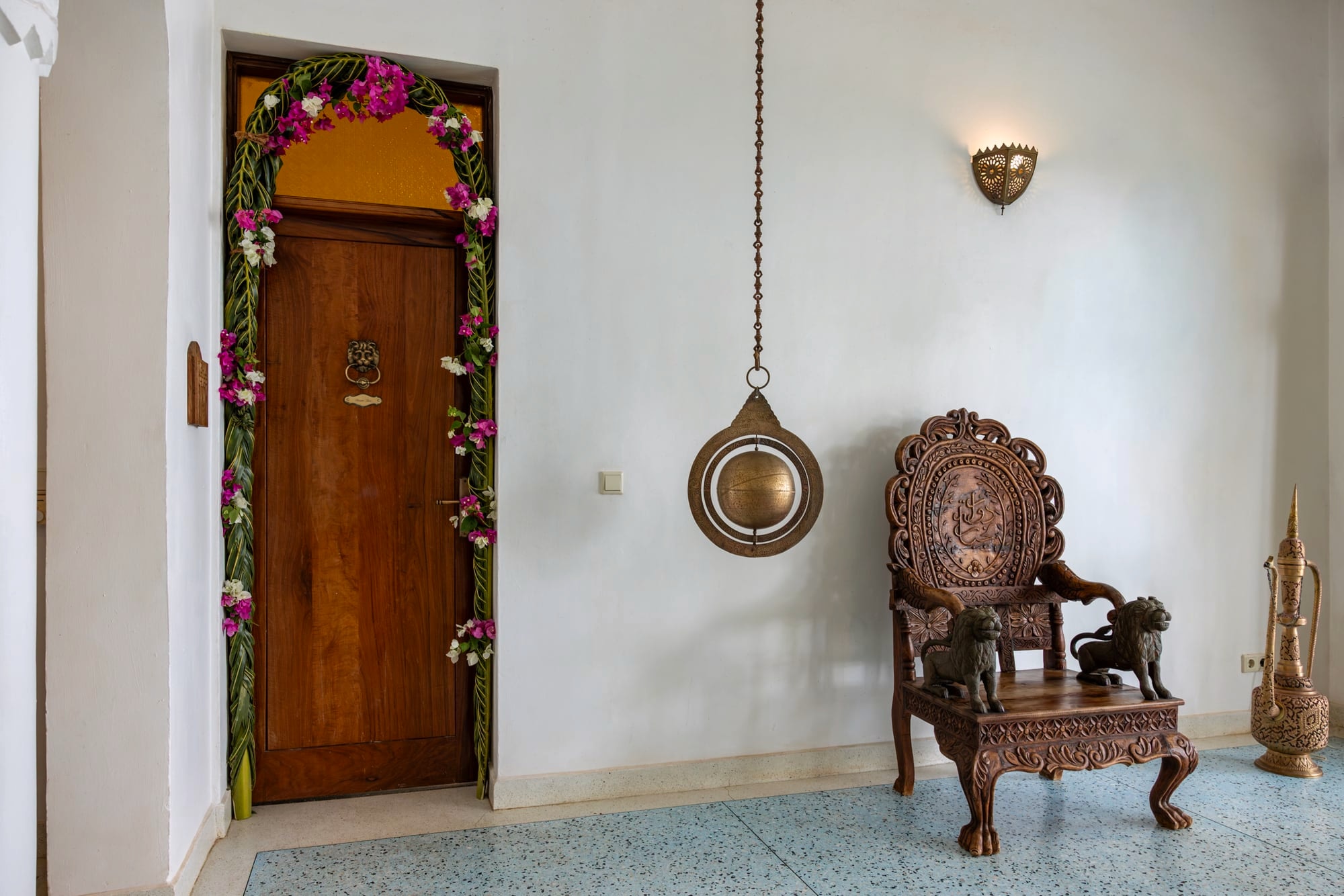 The lounge between the Kidosho rooms, with a carved chair and a doorway dressed with flowers.