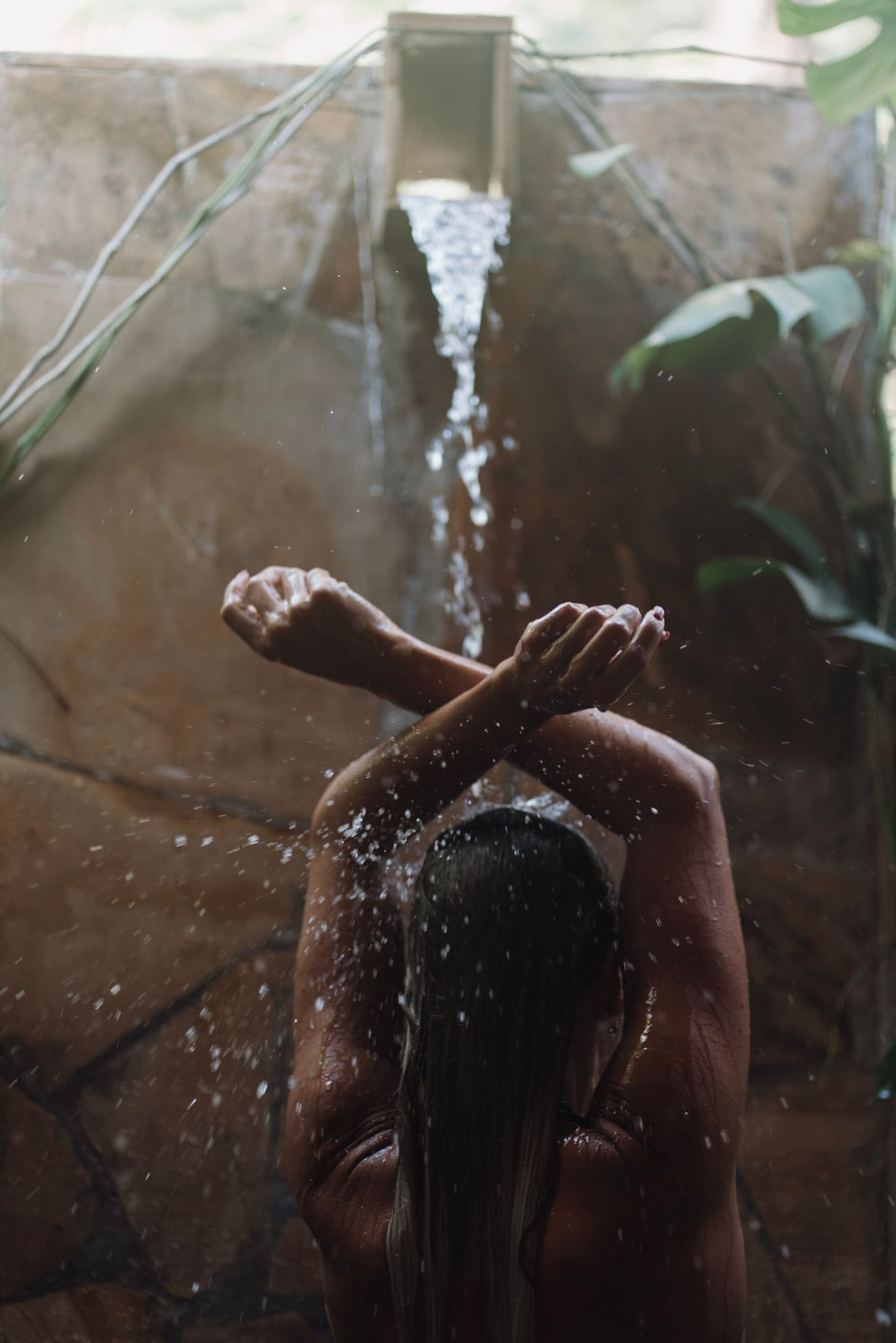 woman relaxing under outdoor shower in Zanzibar during romantic honeymoon experience