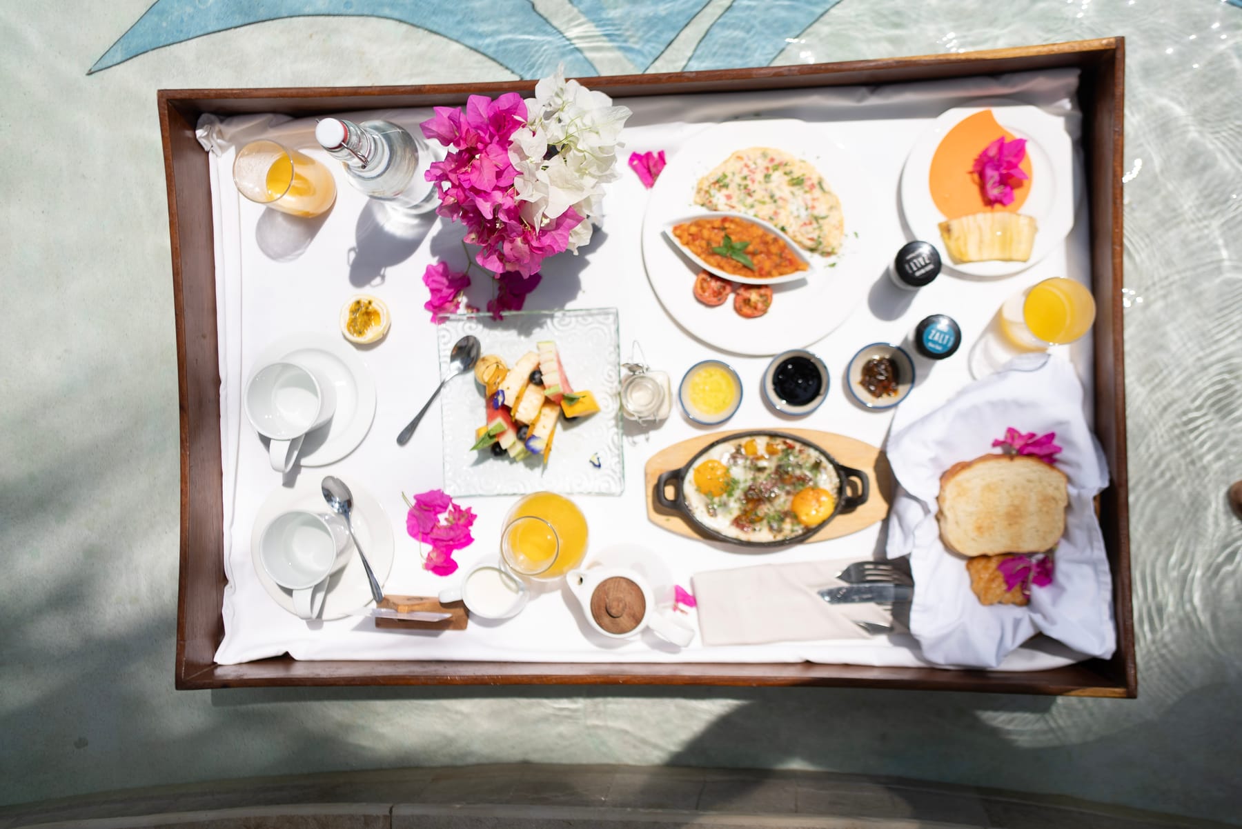 A breakfast tray laden with tropical fruits, eggs and juices