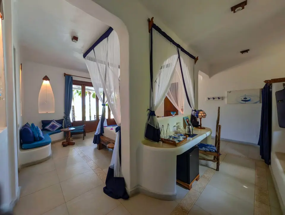 Room Maji interior view at Asili House, Boutique Hotel Matlai Zanzibar, showing wardrobe, safe box, coffee station, yoga mats, and space for an extra bed.
