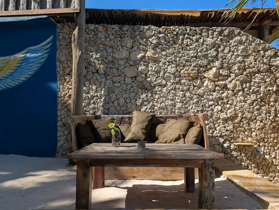 Dhow lounger made from an old boat with coral stone wall and cement angel wings artwork at Boutique Hotel Matlai Zanzibar.