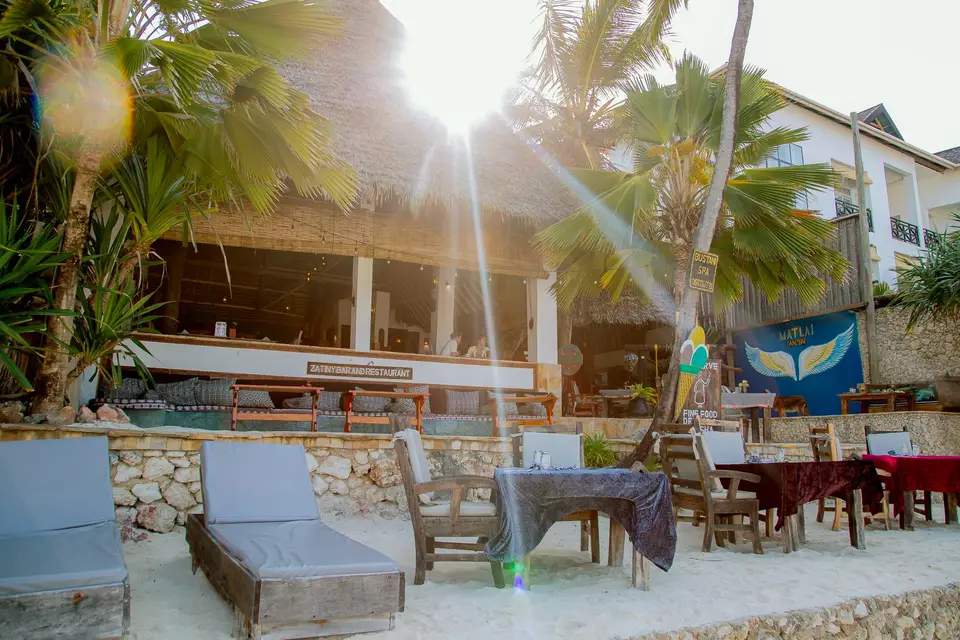 Zatiny Restaurant at Boutique Hotel Matlai Zanzibar viewed from the beach, with beach dining tables, sunbeds, baraza lounge, and beach shower.