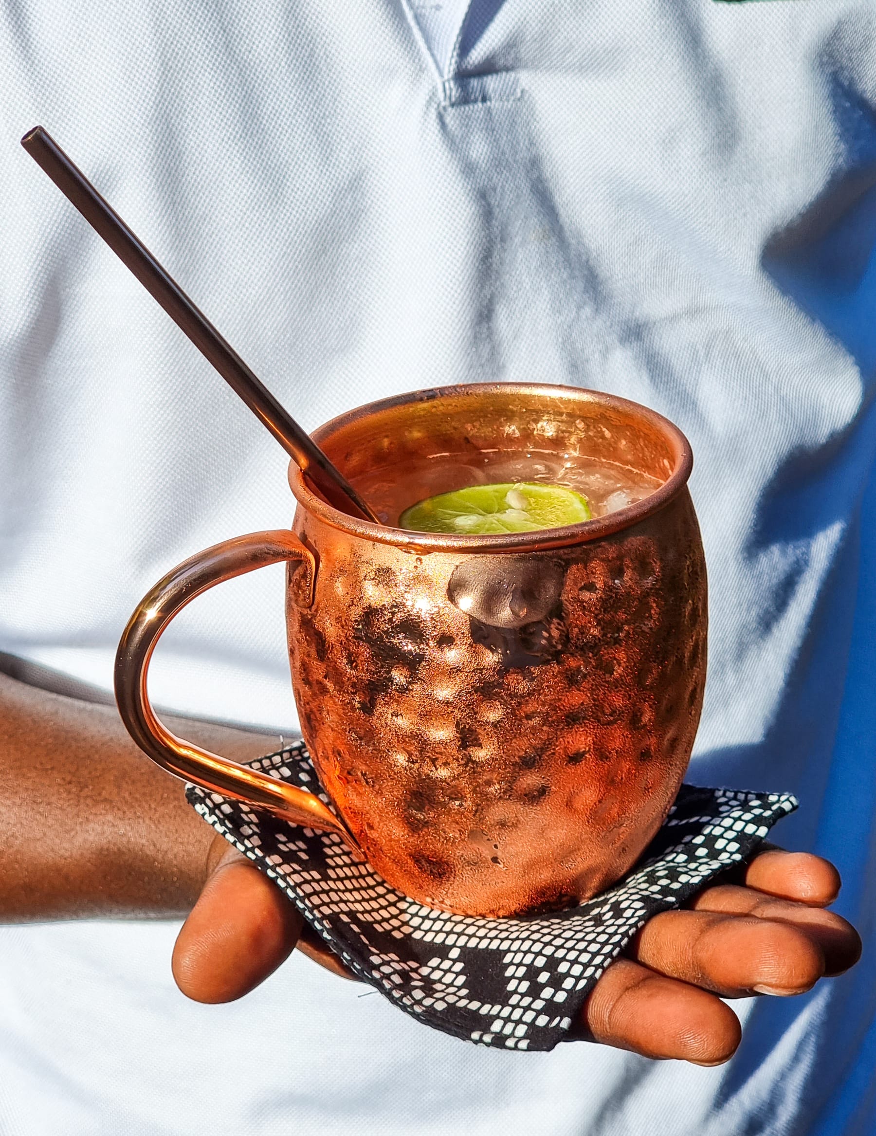A copper Moscow mule mug served on a kitenge cloth at Zatiny